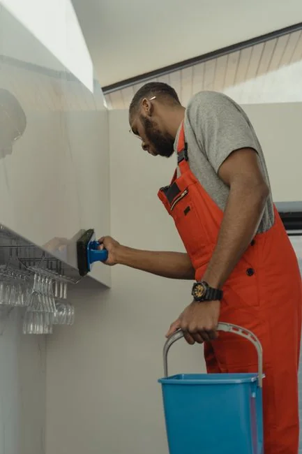 A professional cleaner in protective gear vacuuming the floor in a modern living room.